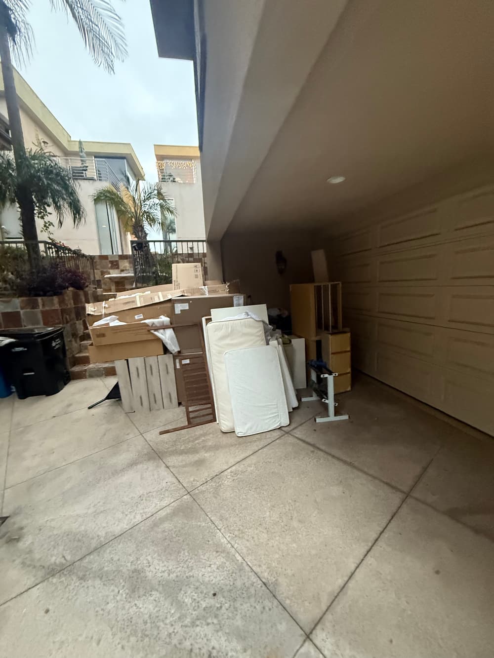 Packed boxes and furniture stacked in a residential garage for moving or storage.