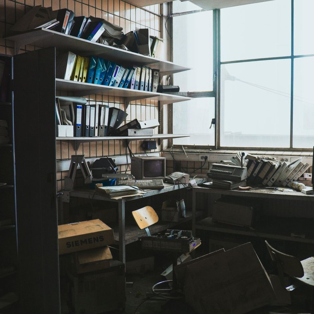 Old office with leftover desks, shelving and equipment waiting to be cleared