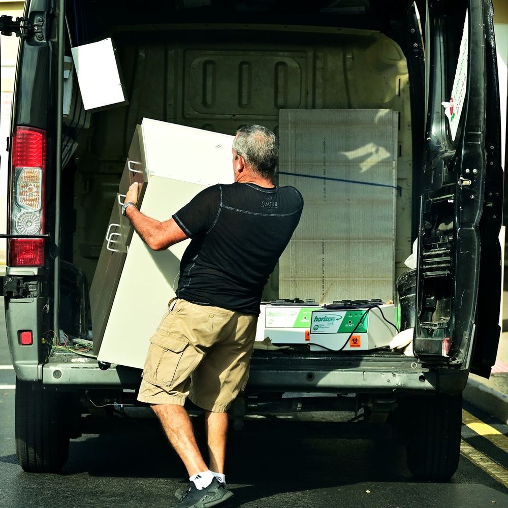 Worker loading a large piece of furniture into a van