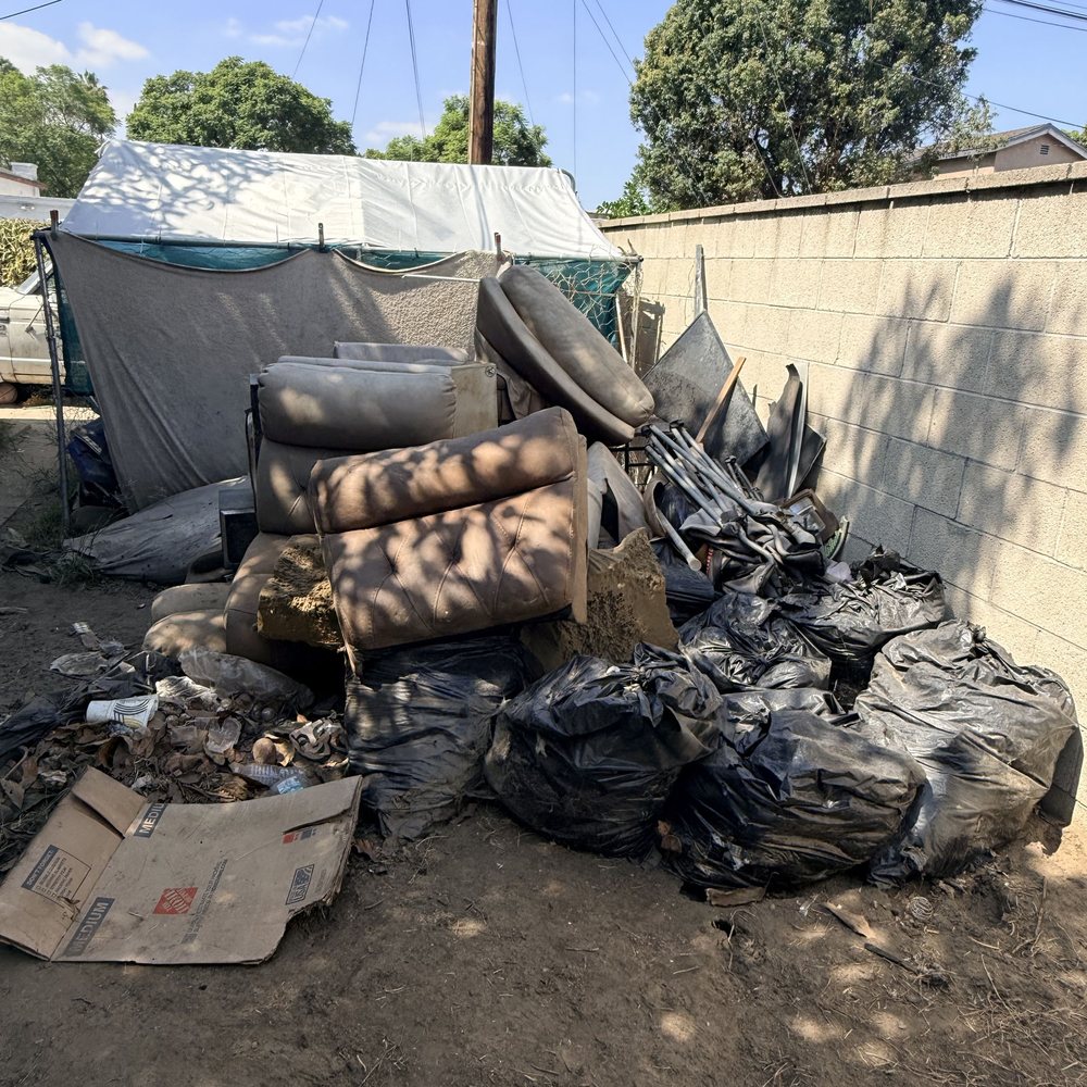 Backyard pile of furniture, bags and debris before a cleanup