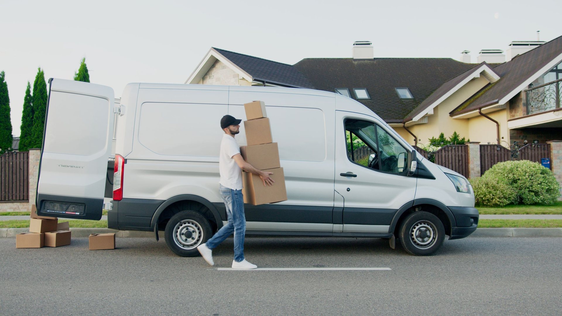 Worker carrying a stack of boxes to a van on a Huntington Beach street