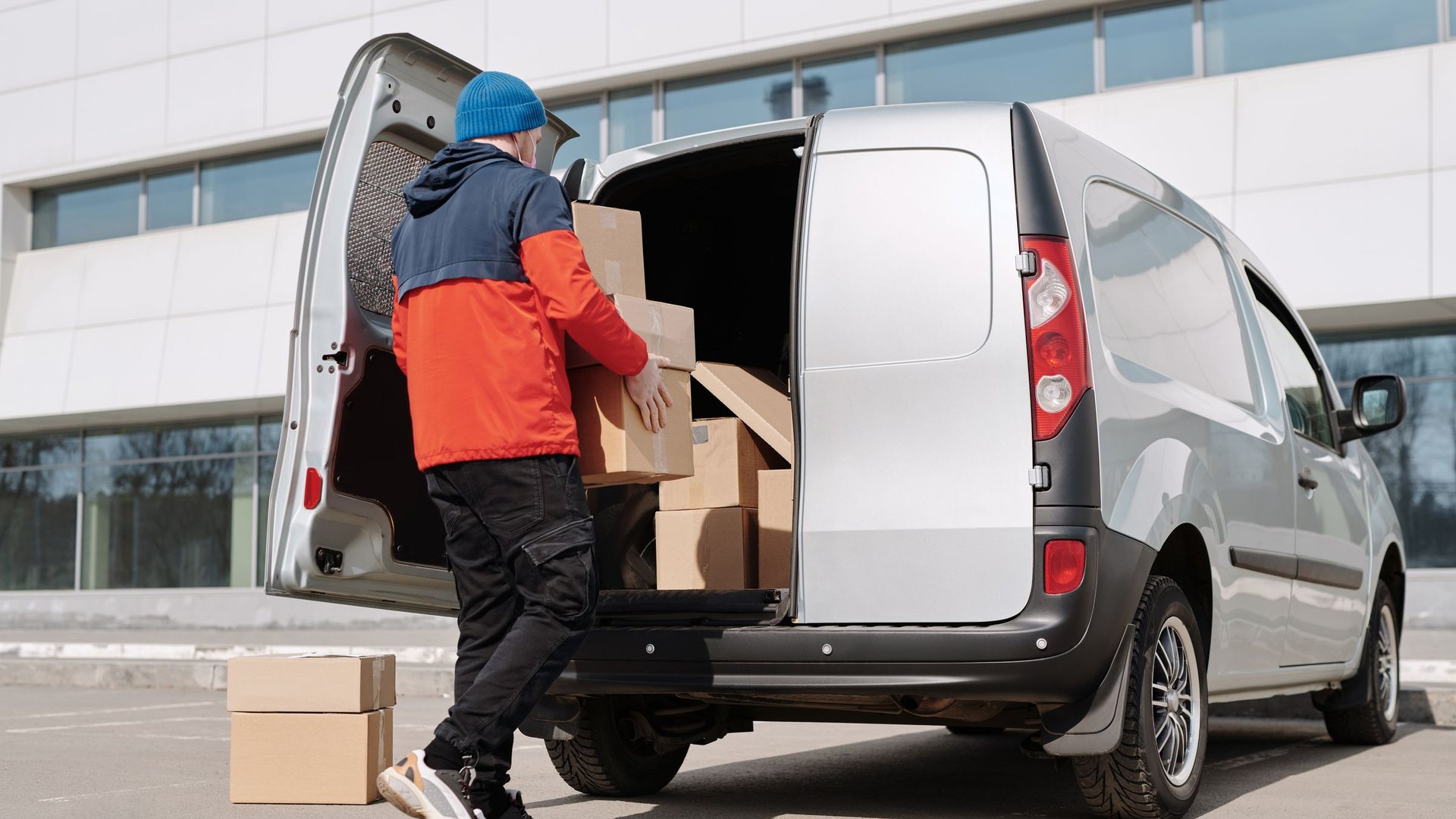 Worker loading boxes into the back of a van outside an Irvine office building