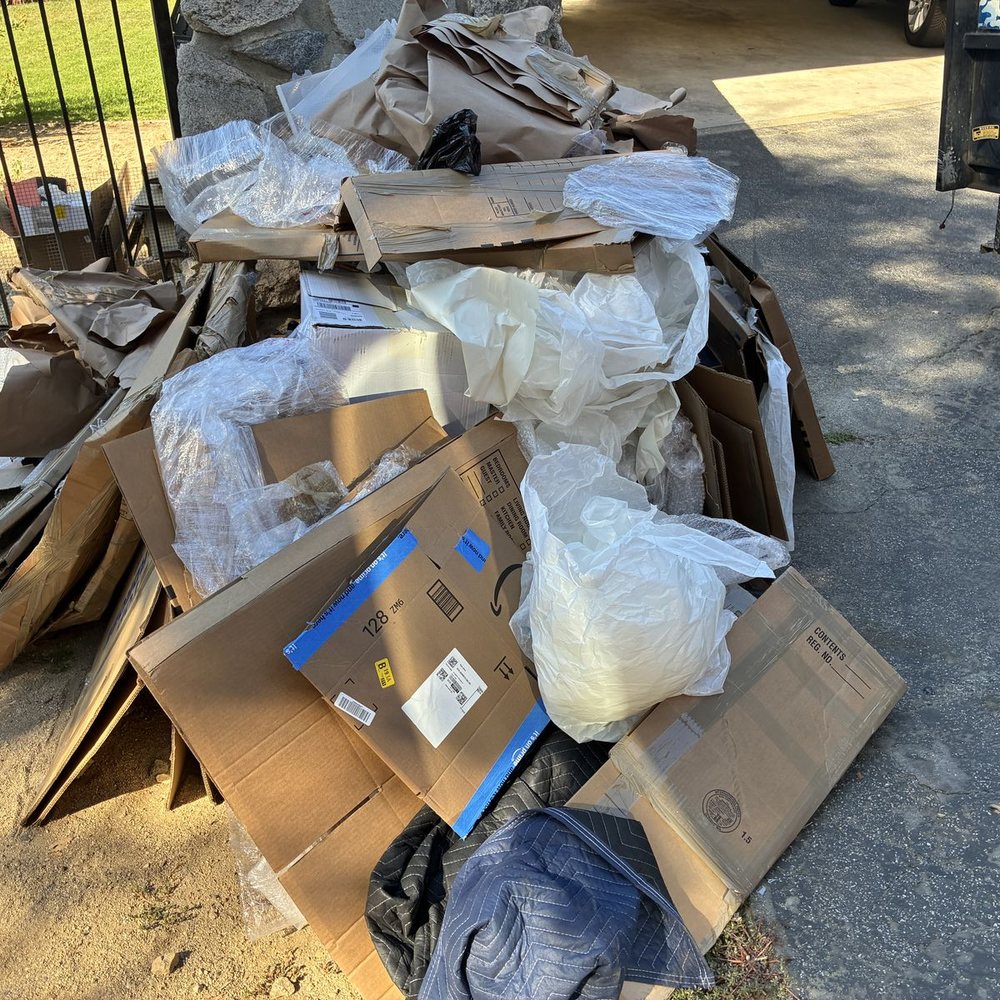 Cardboard, bags and household junk piled in a driveway before removal