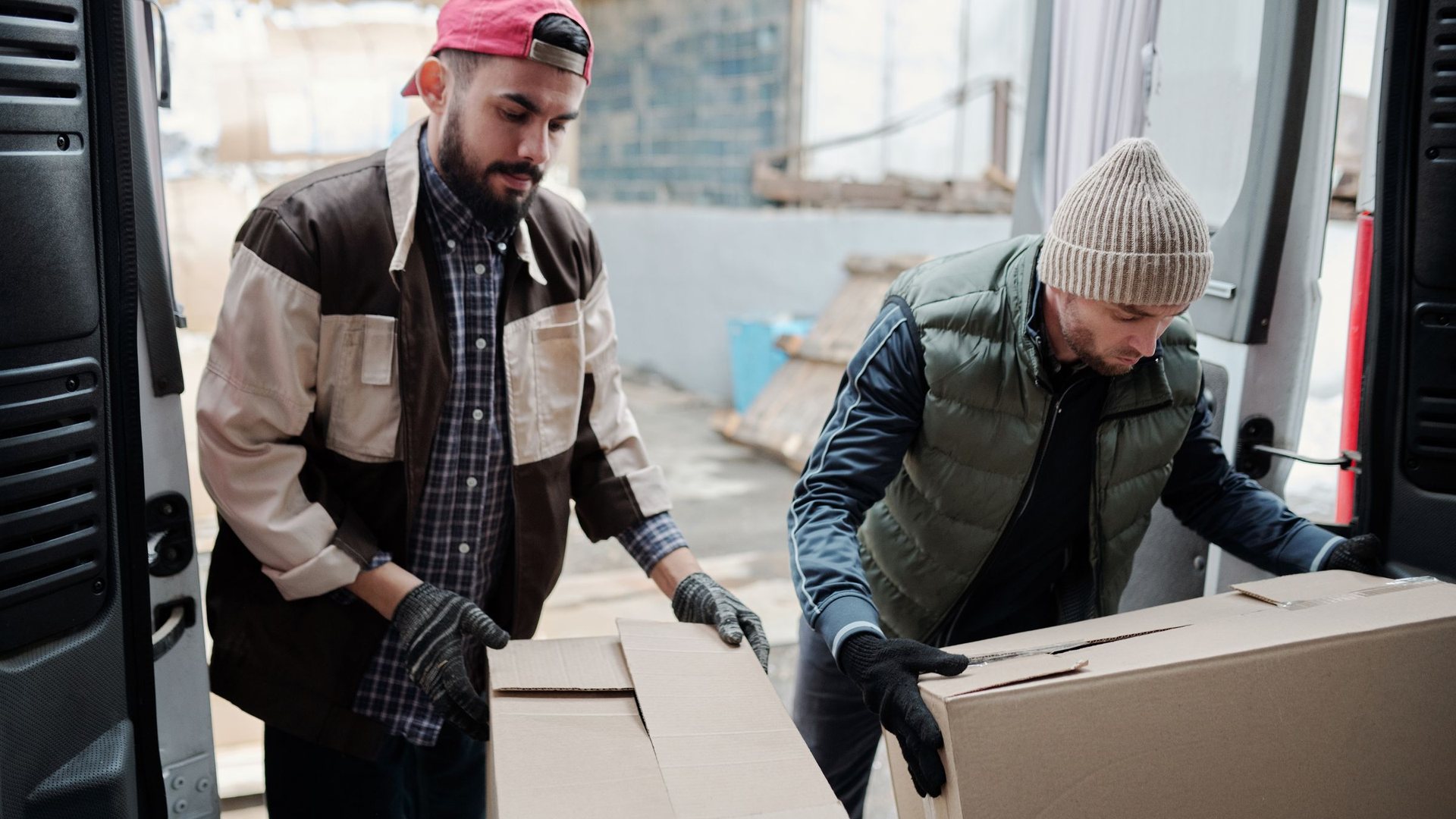 Two workers loading boxes into a van for a Santa Ana junk pickup